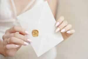 kobieta trzyma zalakowaną kopertę, w której są życzenia ślubne